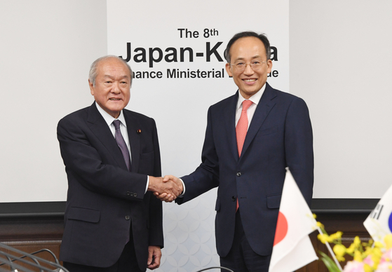 Finance Minister Choo Kyung-ho, right, and his Japanese counterpart Shunichi Suzuki shakes hands at the eighth finance ministers meeting in Tokyo on Thursday. [MINISTRY OF ECONOMY AND FINANCE]