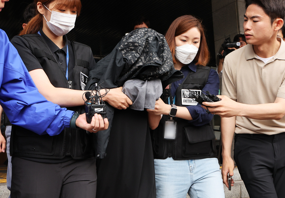 The 35 year-old woman, who had stored her two infants in a freezer at an apartment since 2018, being taken away to the prosecutors’ office from the Suwon Nambu Police Station in Gyeonggi on Friday. The woman is charged with murder instead of the initial infanticide. [YONHAP]
