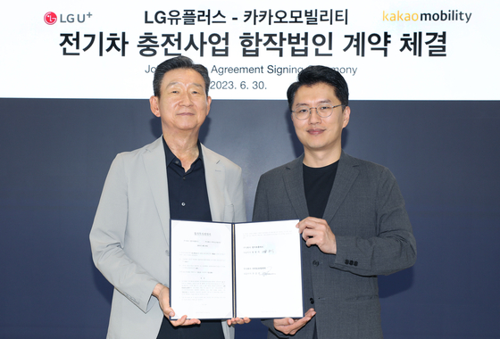 LGU+ CEO Hwang Hyeon-sik, left, and Kakao Mobility CEO Ryu Geung-seon, pose for a photo after signing a joint venture contract to enter the electric vehicle charger business at Kakao Mobility's office in Pangyo, Gyeonggi, on Friday. [LGU+]
