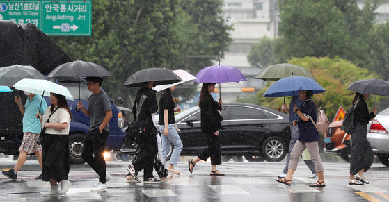 People under an umbrella cross a road in Jongno District, central Seoul as rain falls on June 29. [NEWS1] 