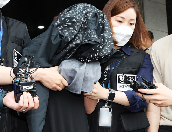 A 35-year-old woman accused of hiding the bodies of two infants in a freezer at an apartment since 2018, is taken to the prosecutors’ office from Suwon Nambu Police Station in Gyeonggi on Friday. [YONHAP]