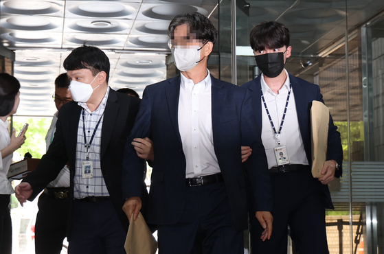 Park Yong-soo, a former aide to previous Democratic Party leader Song Young-gil, is escorted out of his warrant review hearing at Seoul Central District Court in Seocho District, southern Seoul, on Monday afternoon. [YONHAP]