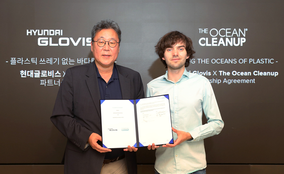 Hyundai Glovis' CEO, Lee Kyoo-bok, left, and Boyan Slat, CEO of The Ocean Cleanup, pose for a photo at Hyundai Glovis' headquarters in eastern Seoul's Seongdong District on Wednesday, commemorating the signing of a partnership aimed at combating the global challenge of ocean plastic waste. Under the partnership, Hyundai Glovis will install cameras on their vessels to gather data on the location and size of floating plastic waste, which will then be shared with the Dutch non-profit organization. Furthermore, Hyundai Glovis will provide logistical support for the transportation of The Ocean Cleanup's specialized equipment, including purpose-built barges designed to collect plastic waste from the ocean's surface. [HYUNDAI GLOVIS]