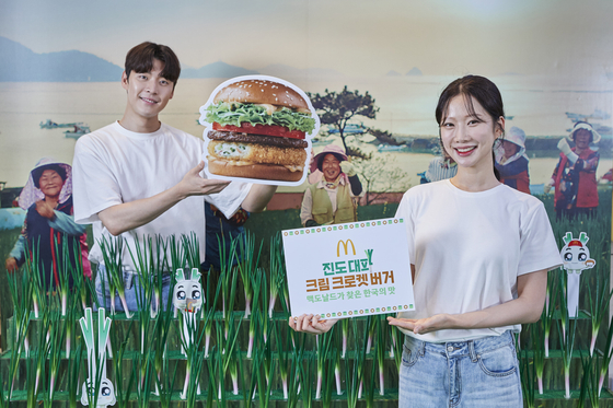 Models pose with an image of the Jindo Green Onion Cream Croquette Burger, the third menu item of McDonald's Korea's Taste of Korea project and made using approximately 50 tons of green onions from Jindo Island off the southwestern tip of the Korean peninsula. [MCDONALD'S KOREA]