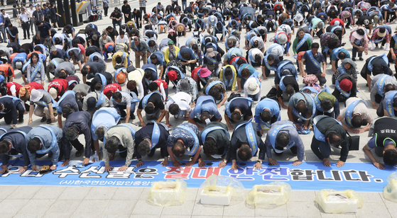 Members of a fishermen federation bow down in a pledge to assure the safety of Korean fishery products at Busan Station Plaza on Monday. [YONHAP]