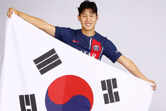Lee Kang-in poses with the Korean flag while wearing a Paris Saint-Germain shirt in a photo released by the club on Saturday.  [PARIS SAINT-GERMAIN]