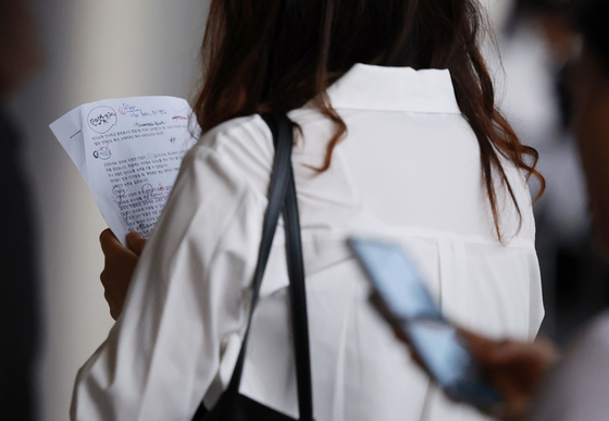 A visitor reviews her resume before having a mock interview at a job fair held at Coex, southern Seoul, on July 3. [YONHAP]