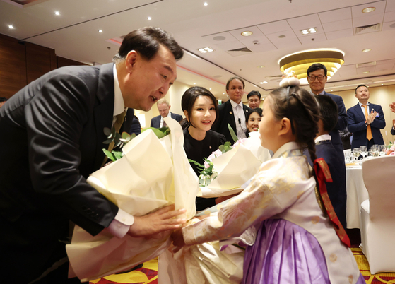 Prezydent Yoon Suk Yeol (z lewej) otrzymuje bukiet kwiatów od dziewczyny w Hanboku podczas spotkania z mieszkańcami Korei w Polsce w hotelu w Warszawie w środę. [JOINT PRESS CORPS]