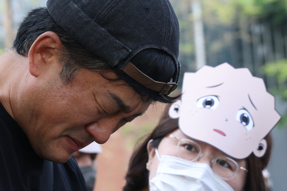 Lee Woo-jin, the younger brother of late cartoonist Lee Woo-young, illustrator of the “Black Rubber Shoes” (1992-2007) children’s comic series, sheds tears in front of the Hyungseul Publishing building in Paju, Gyeonggi, on May 15 during a funeral rally. [YONHAP]