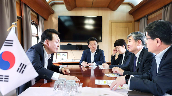 Korean President Yoon Suk Yeol, left, holds a meeting with aides to discuss a response to damage from heavy rains in Korea on the train en route to Warsaw, Poland, after a bilateral summit with Ukrainian President Volodymyr Zelensky in Kyiv on Saturday. [PRESIDENTIAL OFFICE]