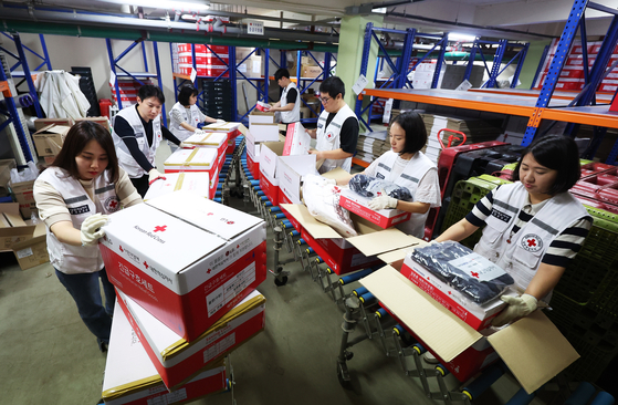 Employees at the Gyeonggi branch of the Korean Red Cross on Monday pack emergency disaster relief kits to deliver to the regions impacted by the recent deadly downpours. [YONHAP]