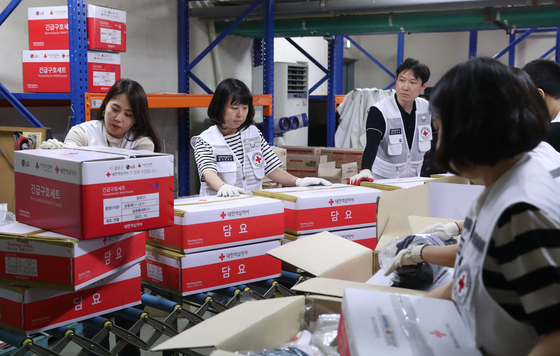 Employees of the Korean Red Cross on Monday pack disaster relief kits to deliver to the regions impacted by the recent deadly downpours. [NEWS1]