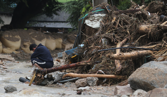 The owner of a house in Yecheon County, North Gyeongsang, slumps to the ground on Sunday morning after coming back to see it destroyed by a landslide. [YONHAP]