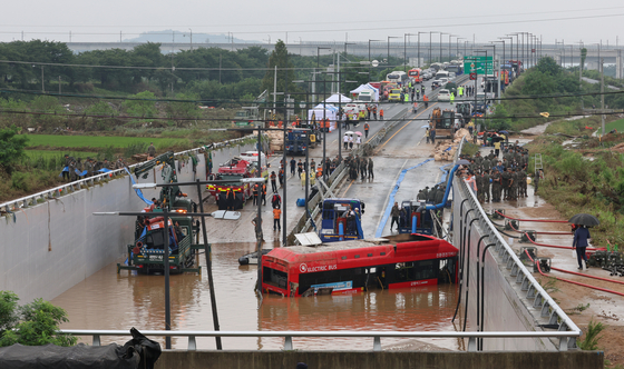 A bus, which was among 15 vehicles trapped inside an underpass in Osong-eup of Cheongju, North Chungcheong, on Saturday after a nearby river overflowed into it, is recovered on Sunday amid a draining operation. At least nine deaths have been linked to the incident. [YONHAP]
