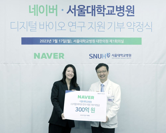 Naver CEO Choi Soo-yeon, left, and Seoul National University Hospital President Kim Young-tae pose for a photo after a donation ceremony at the hospital in Jung District, central Seoul, on Tuesday. Naver will donate 30 billion won to the hospital to support its research in digital health. [NAVER]