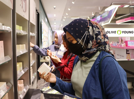 Foreigners look at Korean cosmetic products at an Olive Young store in Seoul. [YONHAP]