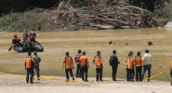 Firefighters and members of the Marine Corps search through a stream in Yecheon County, North Gyeongsang, on Wednesday after a Marine lance corporal was swept away by strong currents that morning. [YONHAP]