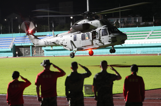 A helicopter carrying the body of a Marine lance corporal who went missing on Wednesday morning in Yecheon County, North Gyeongsang, and was later found dead takes off as his comrades pay their respects. The Marine was in a search operation for heavy rain victims. [YONHAP]