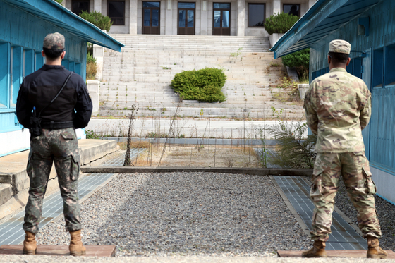 A South Korean soldier, left, and a U.S. soldier, right. face the ground-level concrete slab delineating the Military Demarcation Line (MDL) between the two Koreas at the Panmunjom on Oct. 4. The blue huts on either side are part of the complex known as conference row that straddles the border. [JOINT PRESS CORPS]