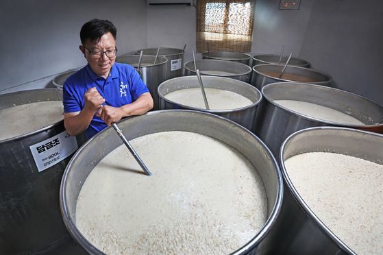Oh Byeong-in, CEO of Haechang Brewery in South Jeolla, stirs a makgeolli (Korean rice wine) mash to supply more oxygen to the microorganisms as part of its fermenting process. [PARK SANG-MOON]