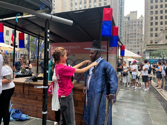 People try out hanbok (traditional Korean clothing) at a booth at the K-tourism Roadshow in New York City last week. [MINISTRY OF CULTURE, SPORTS AND TOURISM]