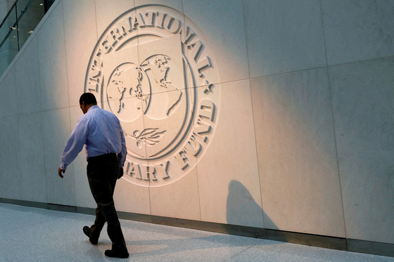 A man walks past the International Monetary Fund (IMF) logo at its headquarters in Washington. [REUTERS]