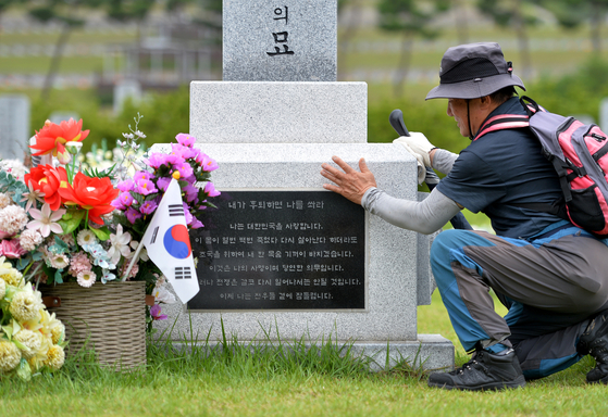 A visitor touches the tombstone of late Gen. Paik Sun-yup at Daejeon National Cemetery on July 7. [JOONGANG PHOTO]