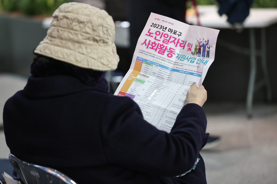 A job seeker reads a flyer at a job fair for seniors held in western Seoul on Dec. 15, 2022. [YONHAP]
