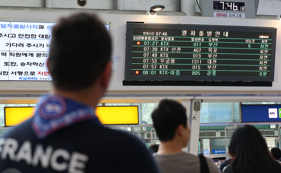 Passengers check their delayed train schedules on an electronic bulletin board at Seoul Station in central Seoul on Wednesday morning. Line 1 subway trains in both directions and KTX and general trains experienced delays for nearly two hours after a man was struck by a KTX train that morning. [YONHAP]