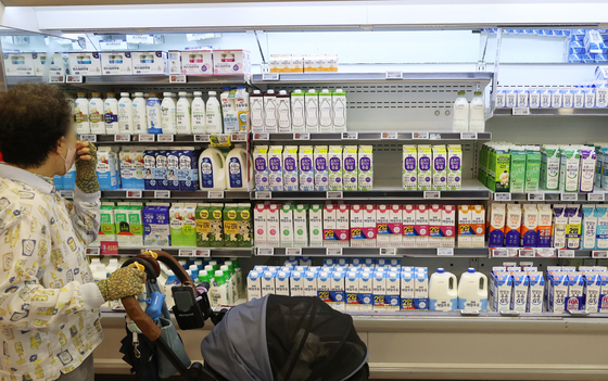 A consumer shops for milk at a discount mart in Seoul on Thursday as the Korea Dairy Committee held its 11th meeting to decide on the raw milk price increase that day. Based on the result of the price-setting negotiation between milk producers and dairy companies, raw milk price is expected to rise by 69 to 104 won (5 to 8 cents) per liter. [YONHAP]