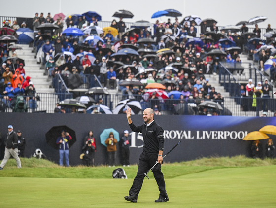 Brian Harman smiles and waves to fans as he celebrates his six-stroke victory on the 18th hole green during the final round of The 151st Open Championship at Royal Liverpool Golf Club in Hoylake, England on July 23.  [GETTY IMAGES]