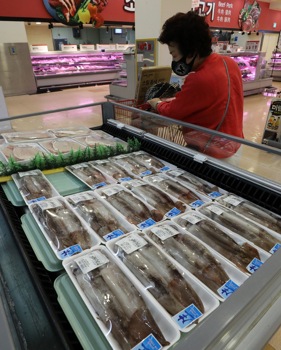 A consumer shops for a squid at a discount mart in Seoul on Thursday. Squid catch from the East Sea dropped significantly by 43 percent year-on-year to 26.2 tons from July 2 to 8, according to the National Institute of Fisheries Science due to the rise of water temperature caused by climate change and overfishing by China. [NEWS1] 