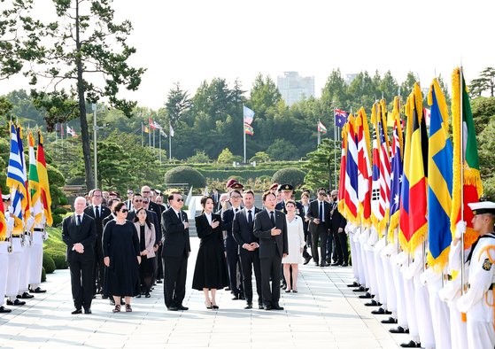 President Yoon Suk Yeol, center, and first lady Kim Keon-hee, second from right, joined by foreign dignitaries, salute the flag as they visit the United Nations Memorial Cemetery in Busan to mark the 70th anniversary of the armistice agreement that ended the 1950-53 Korean War on Thursday. 