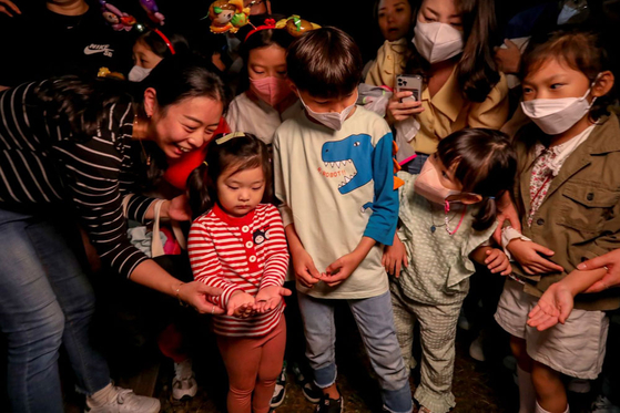 Children hold and observe fireflies at Muju Firefly Festival. [MUJU COUNTY]