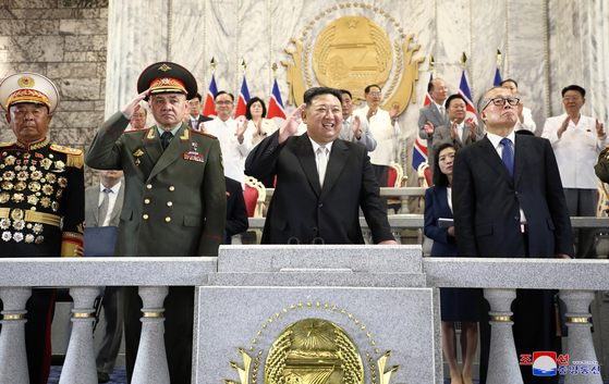 In this photo released by the state-controlled Korean Central News Agency on Friday, North Korean leader Kim Jong-un is seen standing on a dais overlooking the military parade that took place in Pyongyang on Thursday night to mark the 70th anniversary of the signing of the armistice that ended the 1950-53 Korean War. On the left stands Russian Defense Minister Sergei Shoigu, while Chinese Communist Party Politburo member Li Hongzhong stands on the right. [YONHAP]