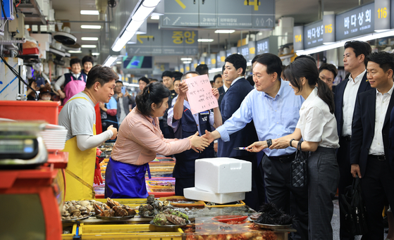 President Yoon Suk Yeol meets with people at the Jagalchi fish market in Busan on Friday. Yoon has yet to go on a vacation although he was planning to take a break at the end of this month and early August. However, various national issues has kept the president from going on a summer vacation. [YONHAP]