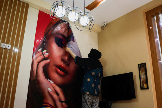 An Afghan beautician removes a poster in a beauty salon in Kabul, Afghanistan, July 24, 2023. [REUTERS/YONHAP]