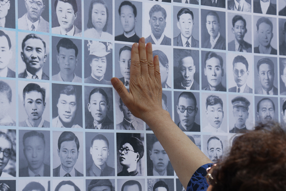 An elderly woman reaches out for a photo of a family member taken by North Korea at the National Memorial Hall of the Korean War Abductees in Paju, northern Gyeonggi, on June 28. [YONHAP]
