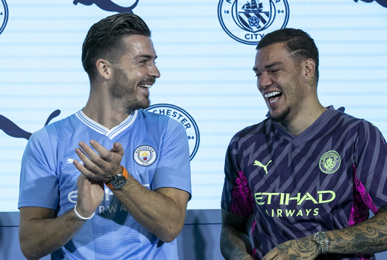 Manchester City's Jack Grealish, left, and Ederson react after spotting a fan in the crowd with a drawn-on copy of Grealish's facial hair.  [NEWS1]