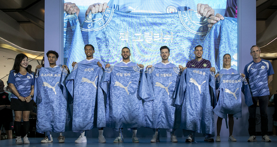 Manchester City players pose with a specially-made City hanbok, or Korean traditional dress, at Lotte World Mall in southern Seoul on Saturday.  [NEWS1]