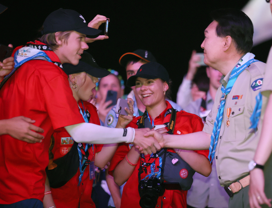 President Yoon Suk Yeol in a scout uniform shakes hand with a scout member at the official opening of the 12-day World Scout Jamboree held at Saemangeum, Buan County, North Jeolla on Wednesday. [NEWS1]