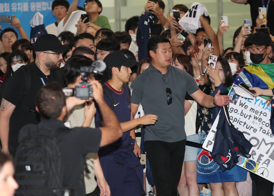 Fans try to take a photo of Lee Kang-in, center, as he arrives at Gimhae International Airport in Busan with his Paris Saint-Germain teammates on Wednesday ahead of a Coupang Play Series preseason friendly against K League club Jeonbuk Hyundai Motors on Thursday.  [NEWS1]