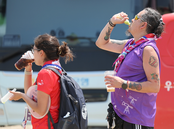 Participants at the World Scout Jamboree held at Saemangeum, North Jeolla, drinking and eating ice cream under the sorching heat at the Delta zone of the camping site on Wednesday. Temperature rose up to 35 degree Celsius (94 Farenheit). [YONHAP] 