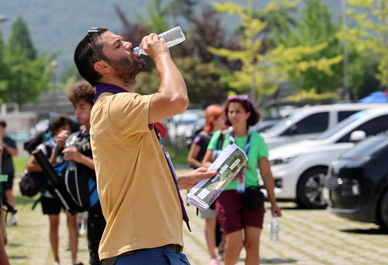 A participant of the 25th World Scout Jamboree held at Saemangeum in Buan County, North Jeolla, quenches his thirst on Tuesday as nationwide temperatures reached 32 to 36 degrees Celsius (90 to 97 degrees Fahrenheit). [YONHAP]
