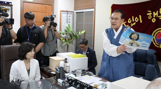 Korea Senior Citizens Association Chairman Kim Ho-il smacks a photo with the face of Kim Eun-kyung, head of the Democratic Party (DP)’s innovation committee, at the association's office in Yongsan, Seoul, on Thursday. [JOINT PRESS CORPS] 