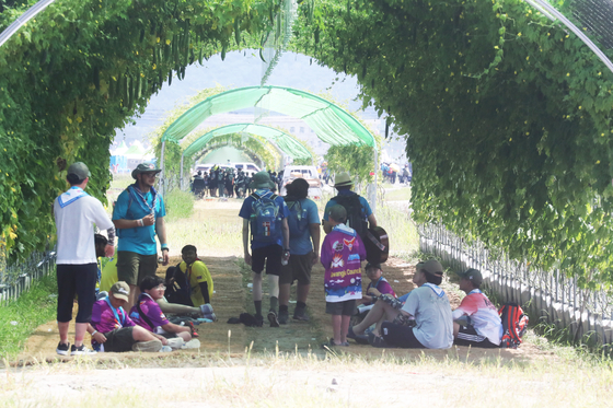 Participants in the 25th World Scout Jamboree find shade under a vine-covered tunnel in Buan County, North Jeolla, on Friday. [YONHAP]
