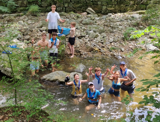 Scouts pose for a group picture while playing in a stream near a Buddhist temple in an undisclosed location. [JOGYE ORDER OF KOREAN BUDDHISM]