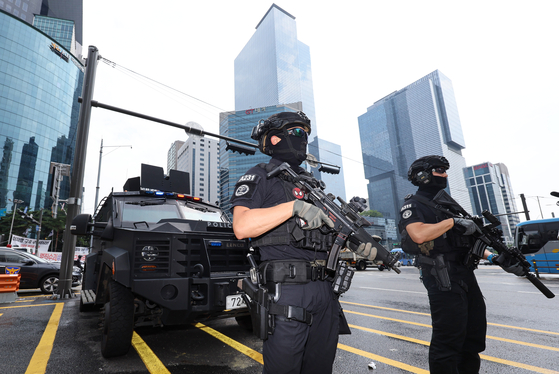 Police commandos and their armored vehicle guard the area near Gangnam Station in southern Seoul on Sunday. Police dispatched additional officers near subway stations and department stores over the weekend amid a flurry of online threats of more stabbings in public spaces. [YONHAP]