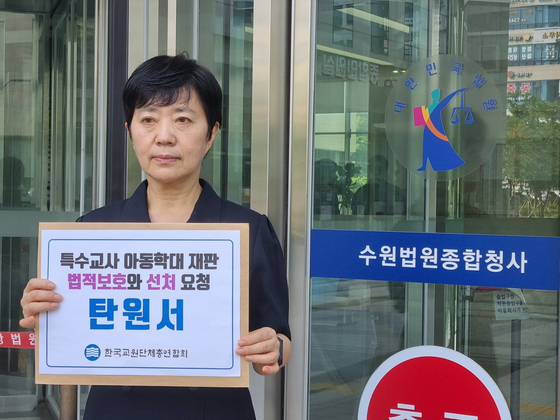 A Korean Federation of Teachers' Associations official on Tuesday holds up a petition the organization filed with a court over a child abuse case between webtoonist Joo Ho-min and a special education teacher. [KOREAN FEDERATION OF TEACHERS' ASSOCIATIONS]