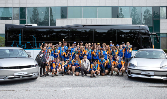 Scouts participating in the World Scout Jamboree take a photo with Hyundai Motor's Universe hydrogen bus, Ioniq 5 and 6 during a tour of the automaker's plant in Jeonju, North Jeolla, on Monday. [HYUNDAI MOTOR]